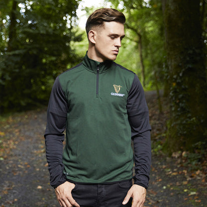 Man wearing a Guinness 1759 quarter zip performance top in dark green with black sleeves and a chest logo.