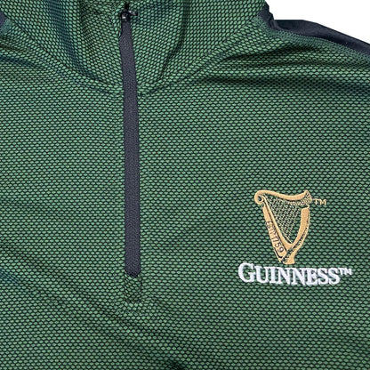 Close up of green textured fabric with a black zipper and Guinness crest embroidery on the chest