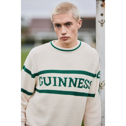 Close-up of a model wearing the cream Guinness Harp Sleeve knit sweater with green stripes.