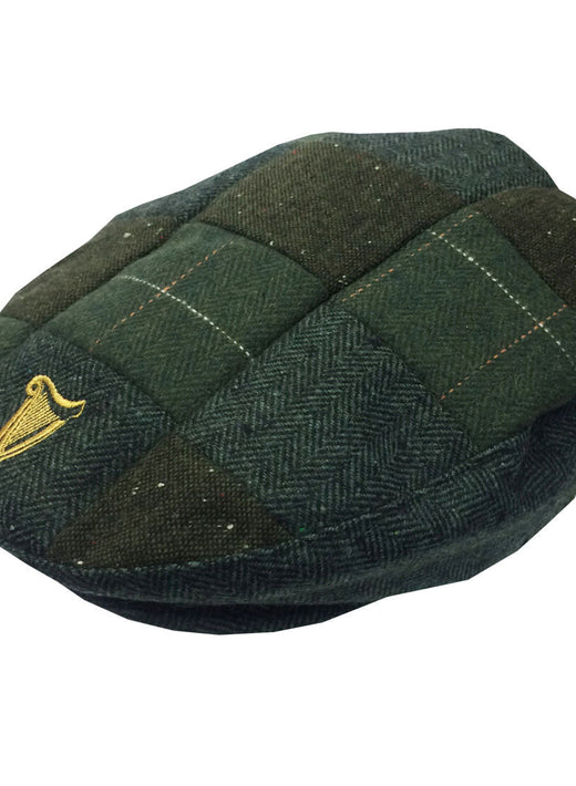 Guinness traditional style tweed patch flat cap in dark green plaid with a gold harp emblem.