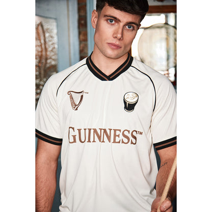 Male model wearing a cream Guinness jersey with brown trim and large GUINNESS lettering