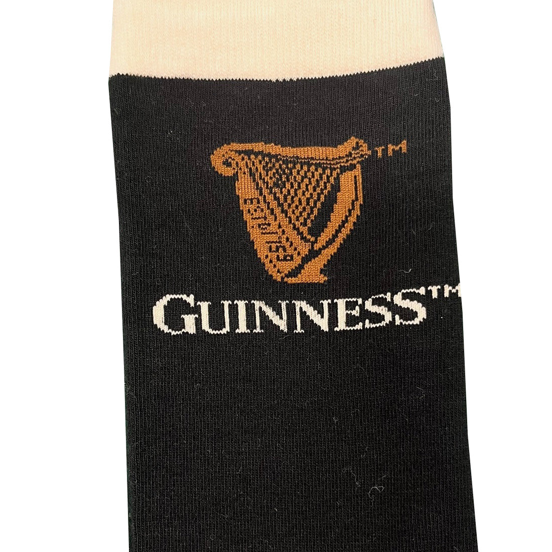 Close-up of Guinness All Over Print Pint Sock in black featuring orange harp logos and GUINNESS lettering