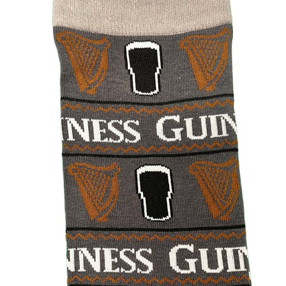 Section of the grey Guinness All Over Print Pint Sock showing orange harps and GUINNESS text around the band