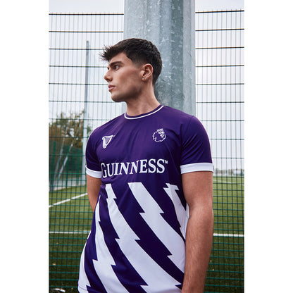 Male model wearing a purple Guinness football top outdoors with GUINNESS logo on the chest and white diagonal pattern.