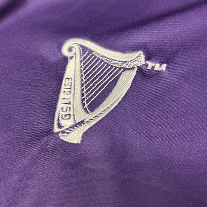Close-up of white Guinness harp crest embroidered on purple football top