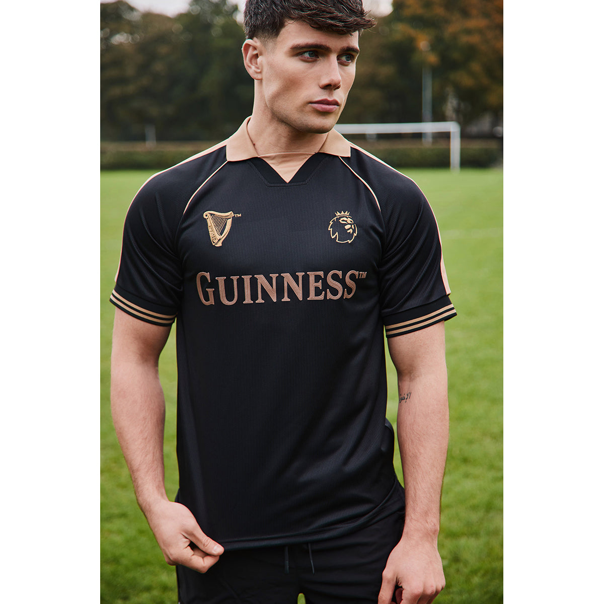 Male model wearing the Guinness black and bronze Premier League football top outdoors
