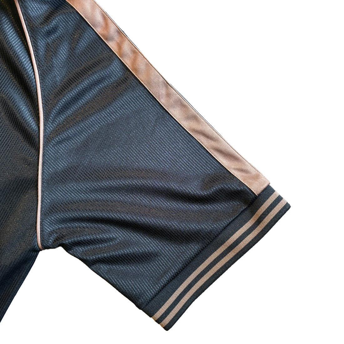 Close up of the dark navy sleeve with tan stripe trim and ribbed cuff from the Guinness football top.