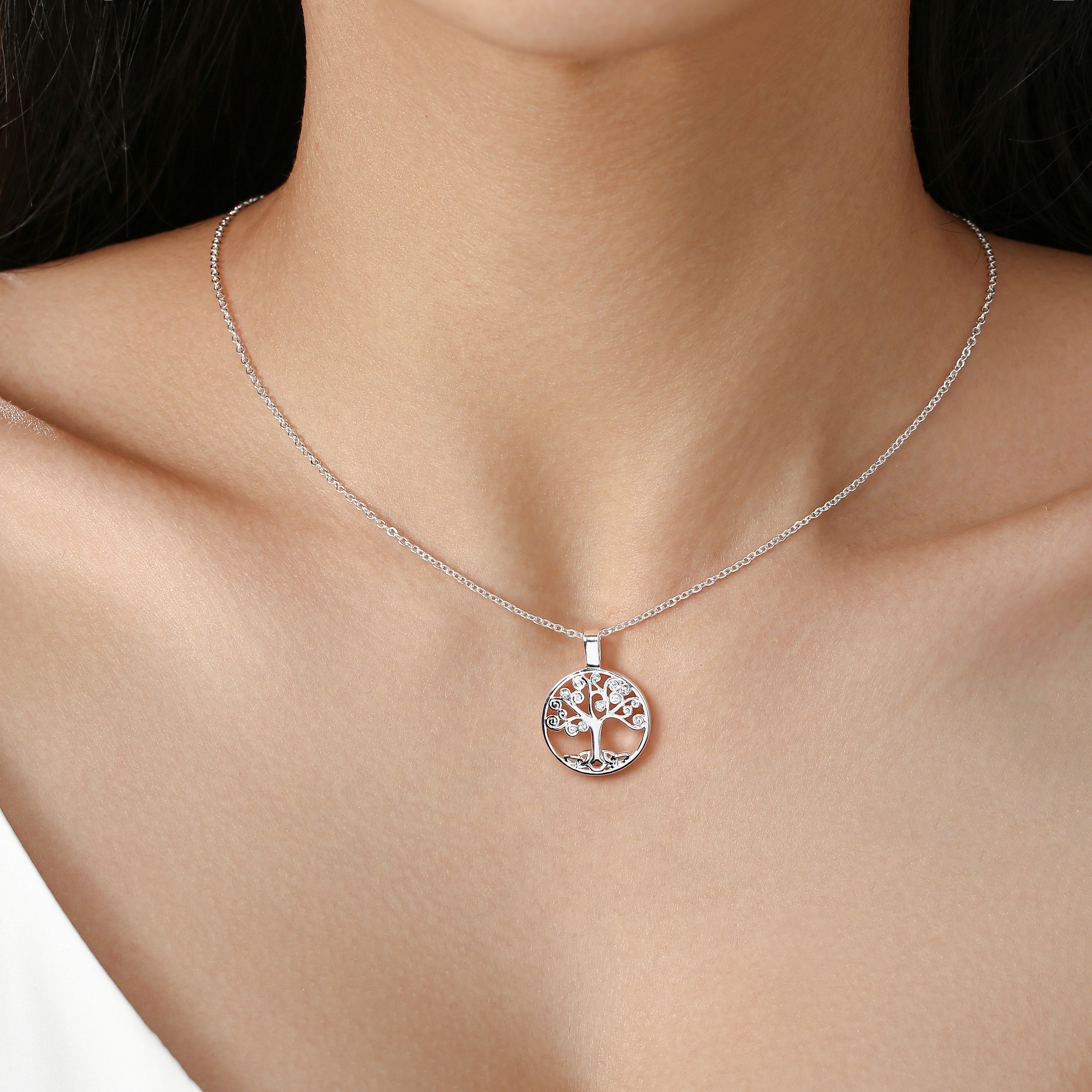 Delicate silver tree of life pendant necklace worn on a model's neck