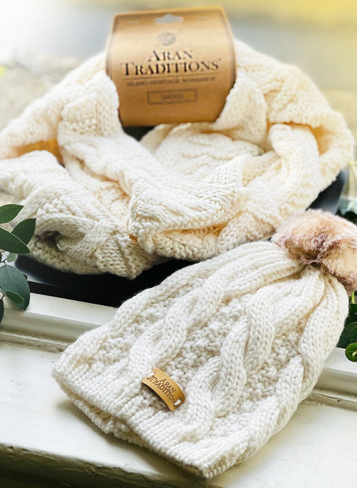 Cream knit snood and matching hat with a fur pom pom from Aran Traditions gift set.