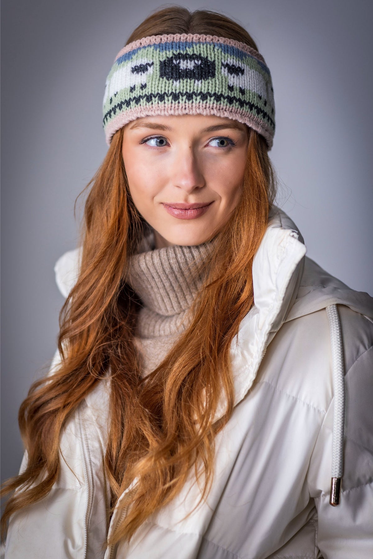 Young woman with long red hair wearing winter clothes and knitted headband
