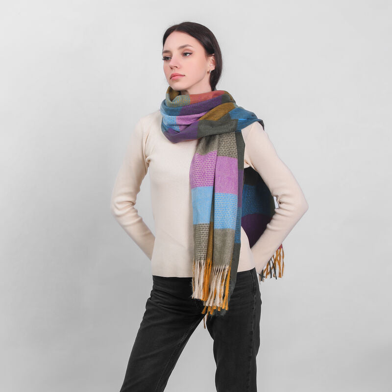 Woman wearing a colorful checkered scarf and cream sweater posing