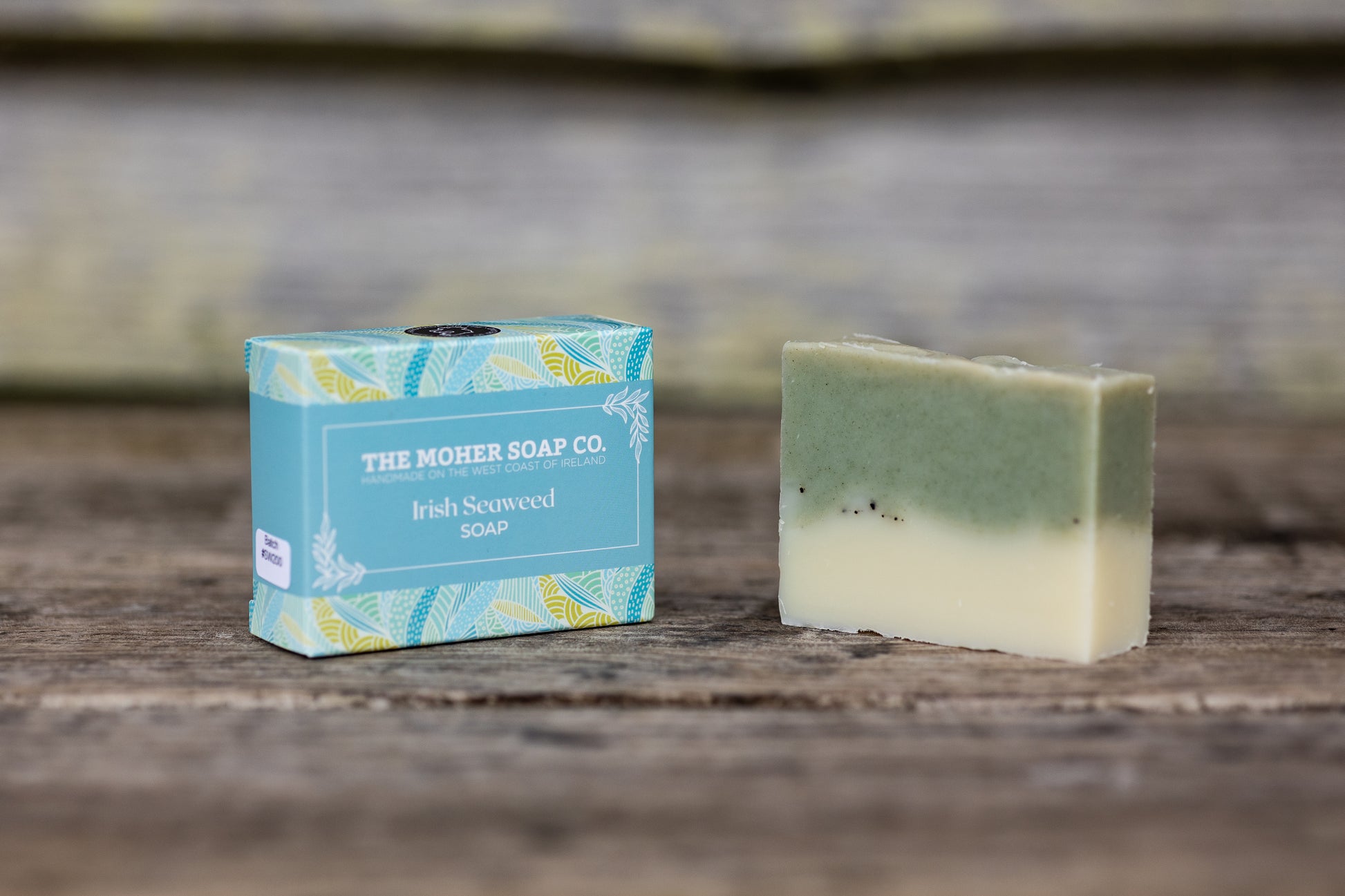 The Moher Soap Co Irish Seaweed Soap bar beside a blue box on a wooden surface.