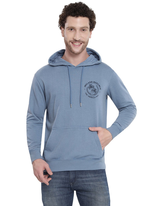 Man wearing light blue acid wash Le Shams hoodie with drawstring hood and front kangaroo pocket plus left chest logo.