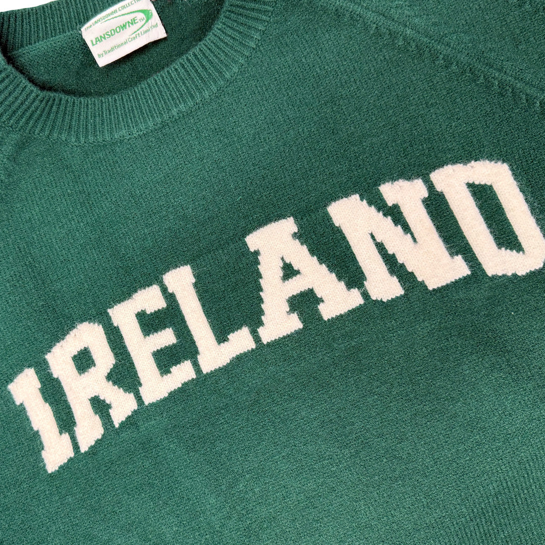 Close-up of green Ireland knitted jumper showing large white IRELAND lettering across the chest