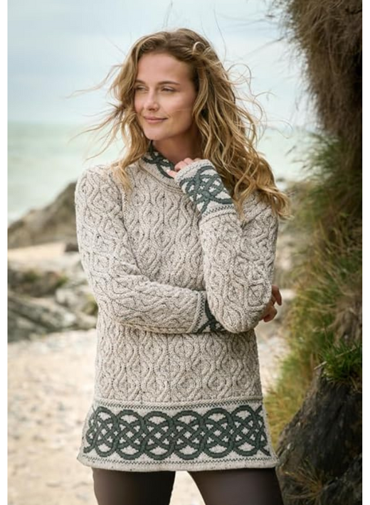 Woman wearing a patterned knit sweater standing outdoors near rocks and grass