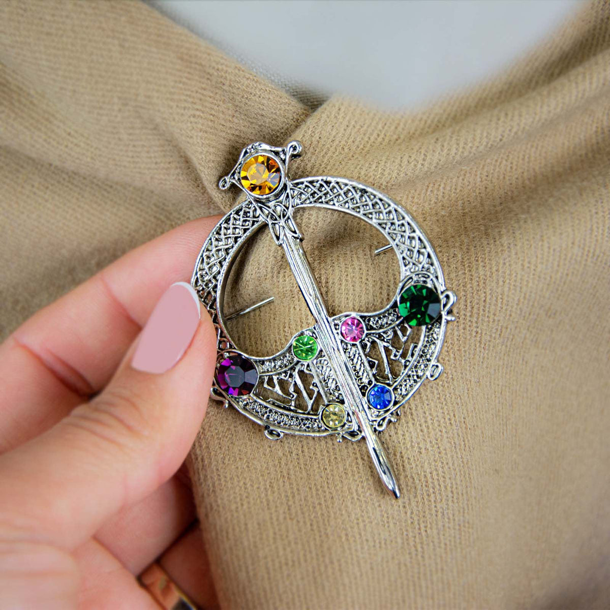 Silver plated full circle Tara brooch featuring a dagger across a lattice circle with multicolored stones.