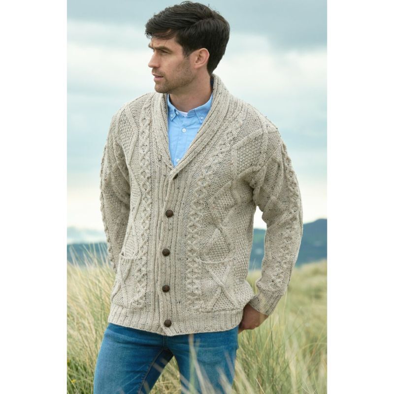 Man wearing beige cable knit cardigan standing outdoors in grassy area