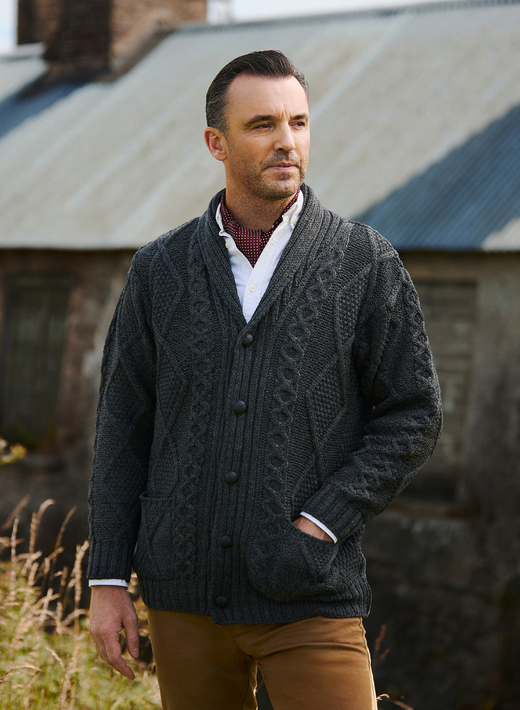 Man wearing dark gray cable knit cardigan and brown pants outdoors