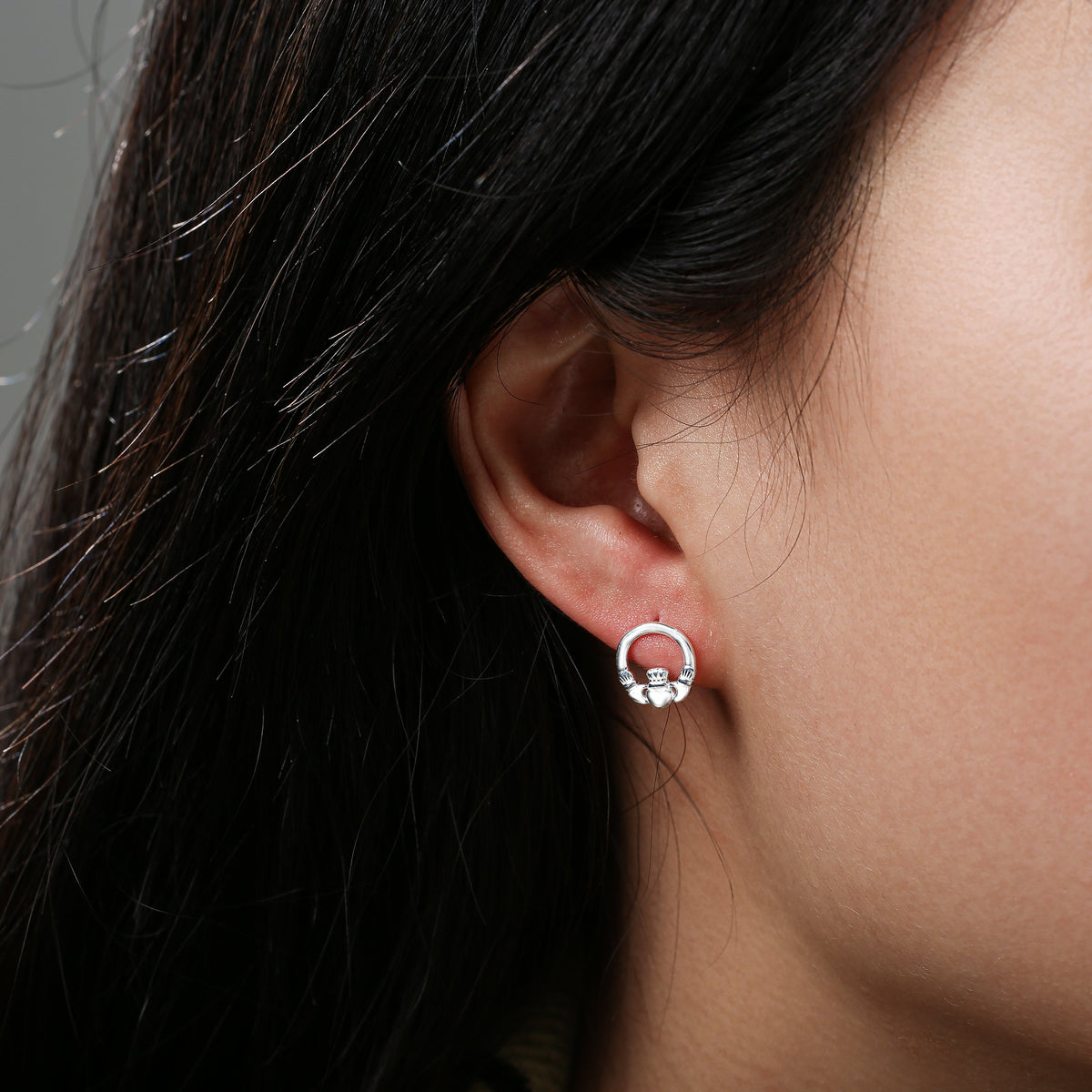 Close-up of ear with silver circular stud earring featuring a heart design