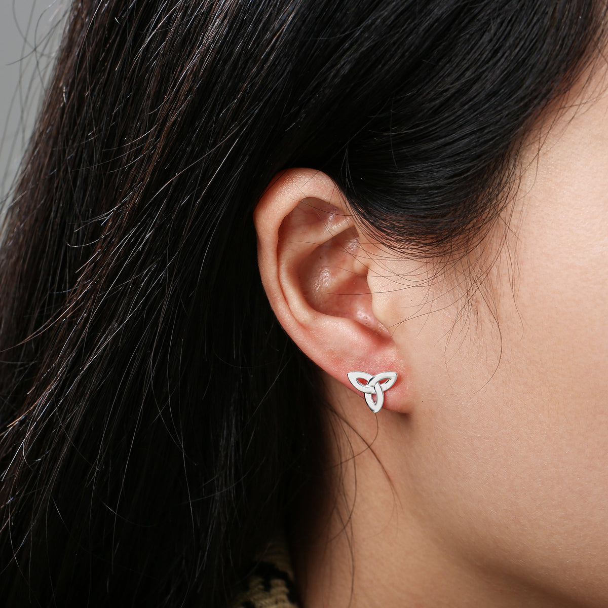 Close-up of ear wearing a silver triquetra knot stud earring