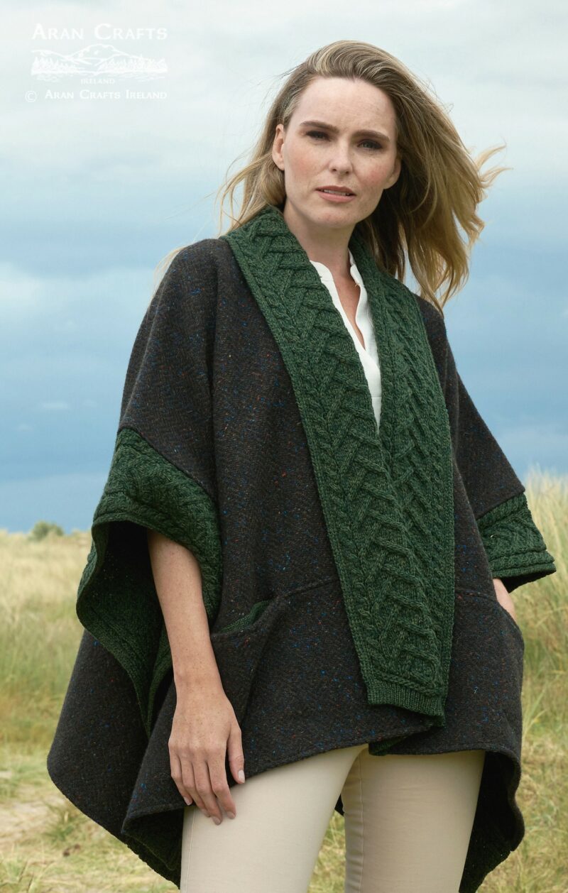 Woman wearing dark Donegal merino cape with green braided trim outdoors