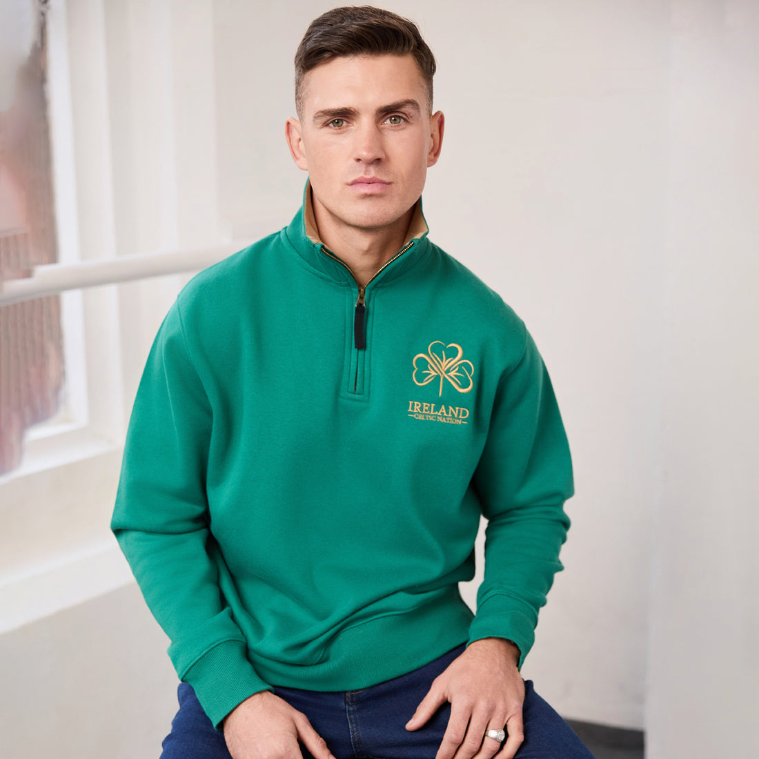 Man wearing green Ireland Premium Quarter Zip Sweatshirt with beige collar and gold chest emblem