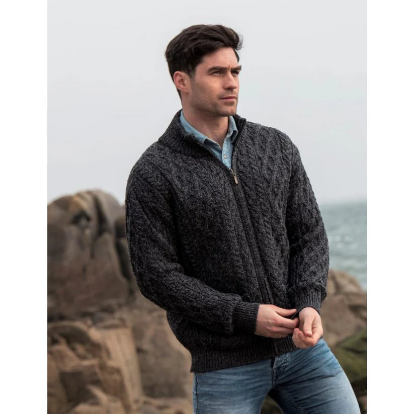 Man wearing dark gray cable knit zip-up sweater near rocky coastline
