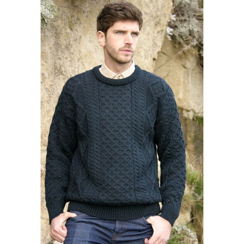 Man wearing dark blue cable knit sweater standing outdoors near rocks