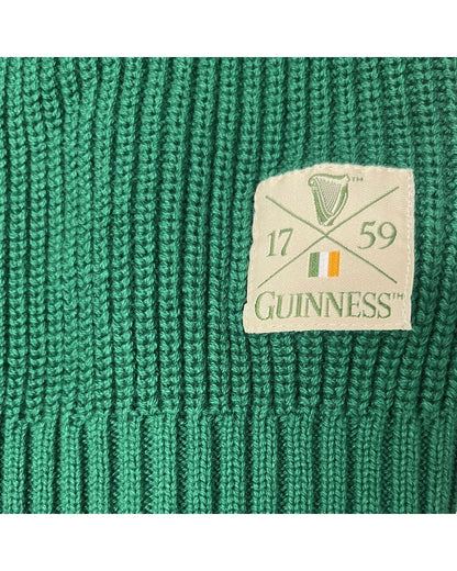 Close up of green knitted fabric with a cream Guinness patch displaying the harp emblem and Irish flag