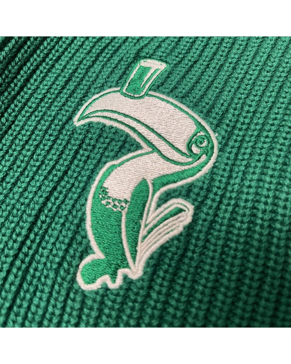 Close up of white and green embroidered crest on the knitted Guinness cardigan