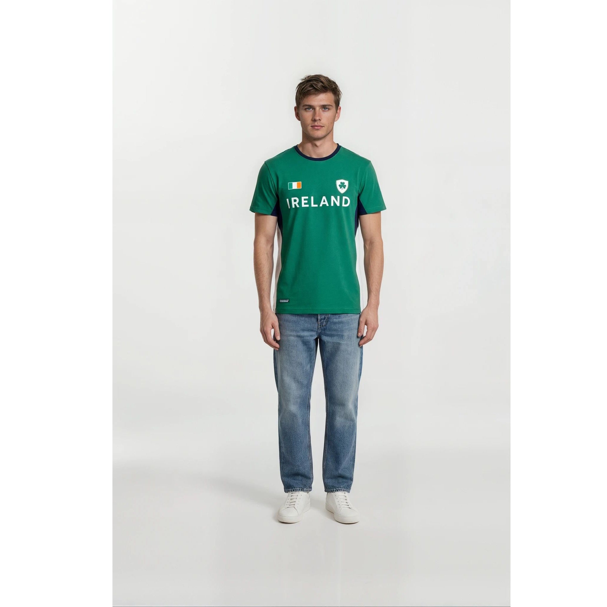 Male model wearing green Ireland Colorblock Unisex T Shirt with crest and flag, paired with blue jeans and white sneakers